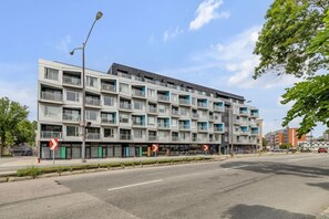 A multi-story residential building with balconies, a street in front, and a clear sky. - Cozy & Co | Le Spritz | Centre-ville + Parking (Québec City)
