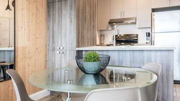 Une cuisine moderne dotée d’un îlot central, d’appareils électroménagers en acier inoxydable et d’une table à manger en verre, assortie de chaises.