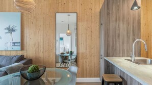 A modern kitchen with a wooden wall, a glass dining table, and a bar area. - Cozy & Co | The GH View | Centre-ville + Parking (Québec City)