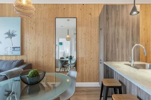 Une cuisine moderne avec un mur en bois, une table à manger en verre et un coin bar.