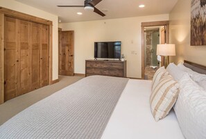 A bedroom with a large bed, a television, a dresser, and a ceiling fan. - Big Sky Escape: Modern 3 BR Condo / Walk to Town - Minutes to Skiing (Big Sky)