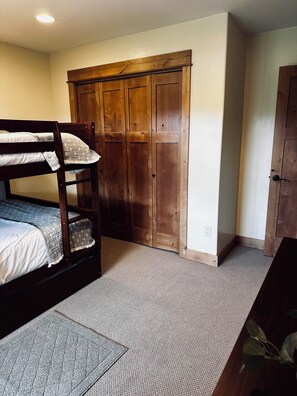 Een slaapkamer met een stapelbed, een kledingkast en een deur.