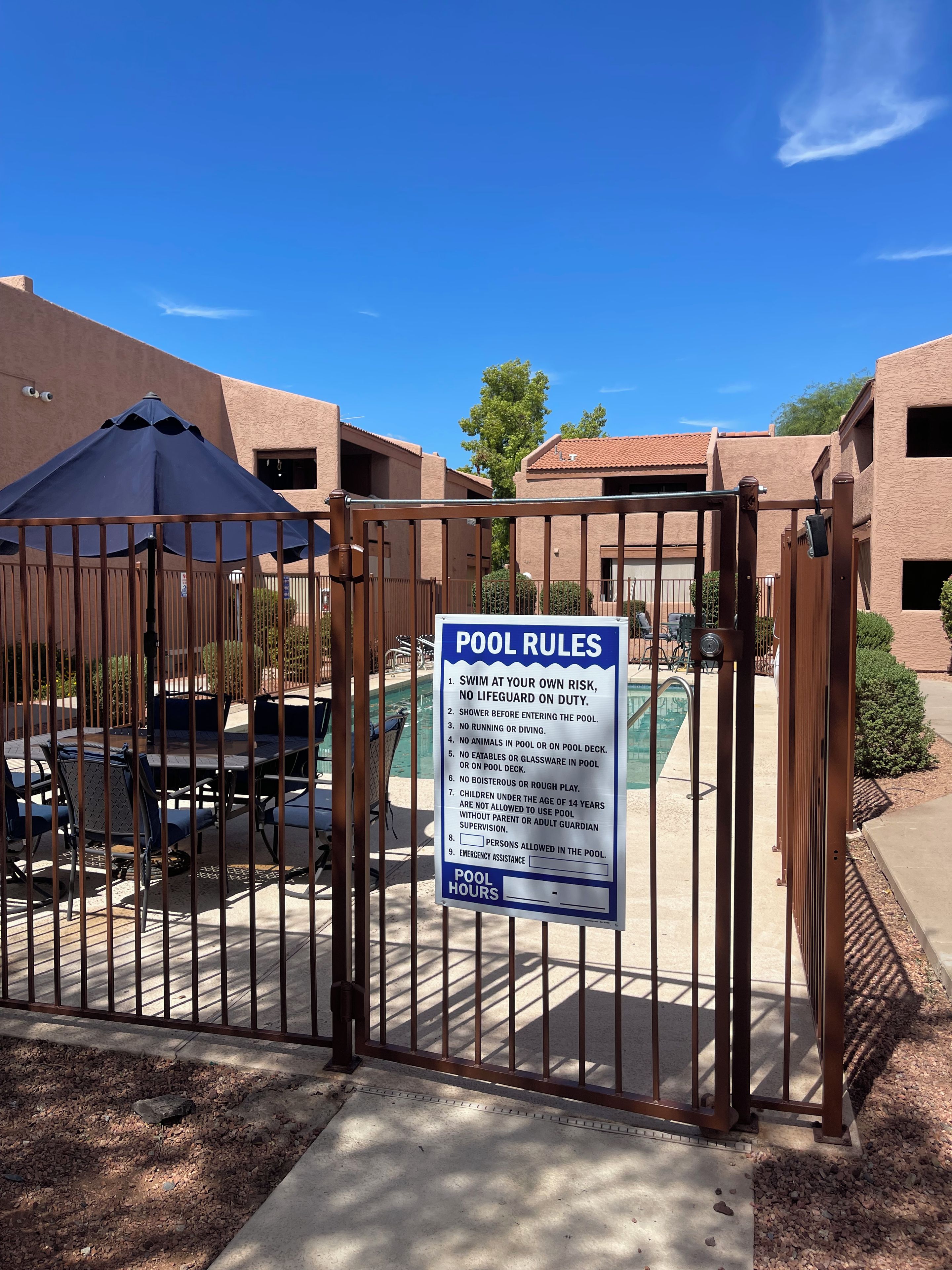 A gated pool area with a sign listing pool rules.