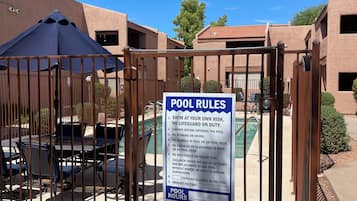 A gated pool area with a sign listing pool rules.
