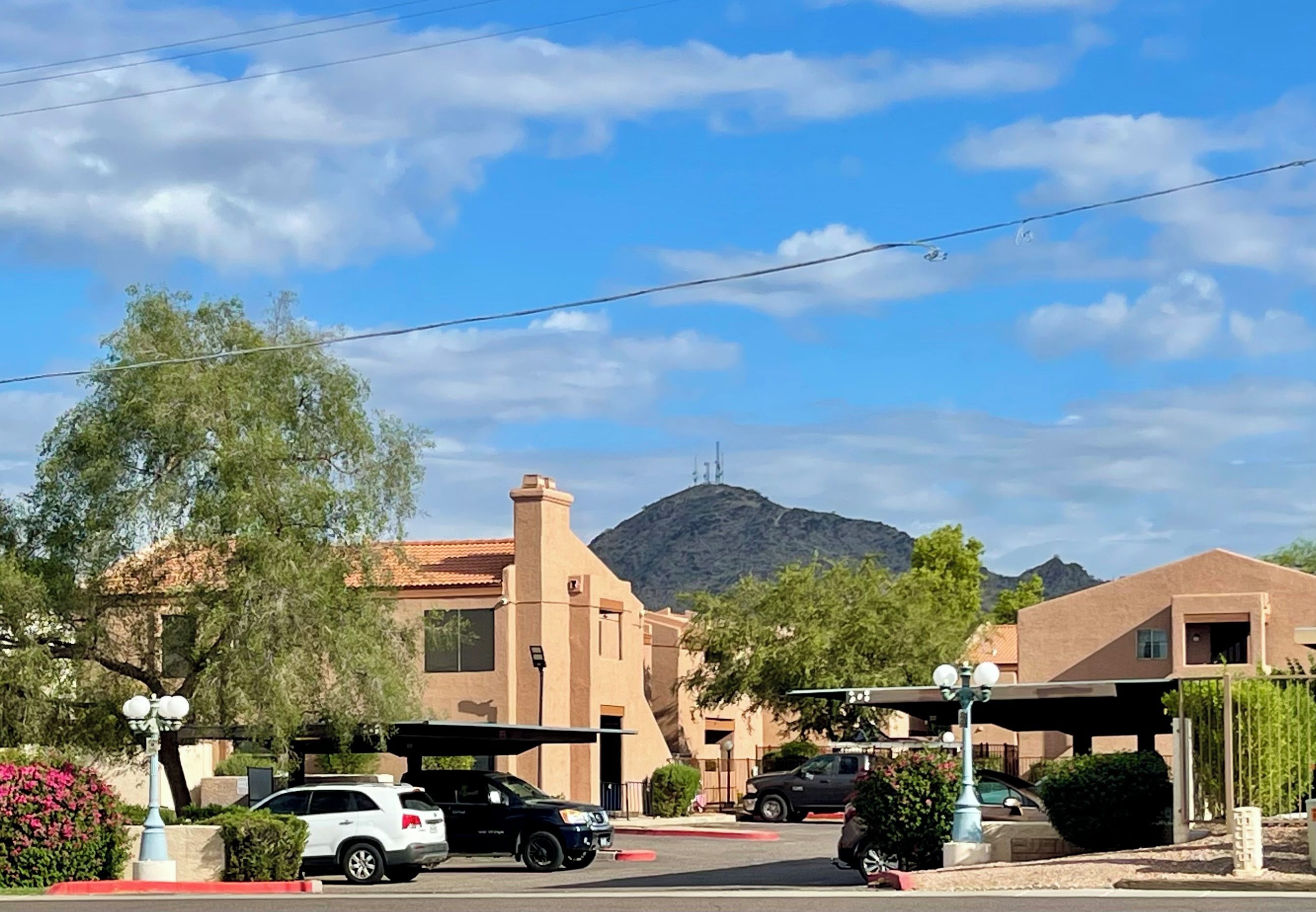 A residential area with houses, a mountain in the background, and parked cars.