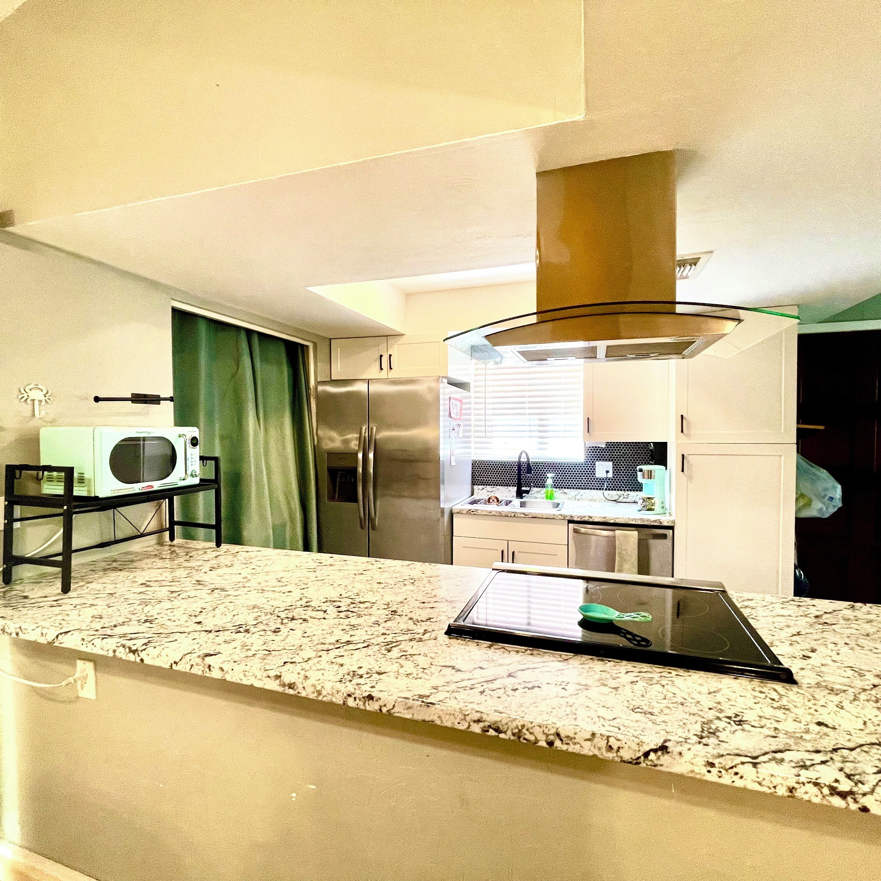 A modern kitchen with a stainless steel refrigerator, a microwave, and a tablet on the counter.