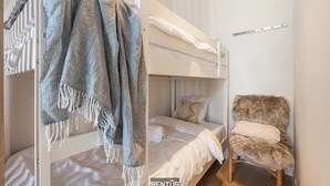 A bunk bed with a blanket and a chair in a room with a white wall and a wooden floor. - DuinGeluk - cosy stay near the sea & marina (Nieuwpoort)