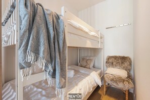 A bunk bed with a blanket and a chair in a room with a white wall and a wooden floor. - DuinGeluk - cosy stay near the sea & marina (Nieuwpoort)