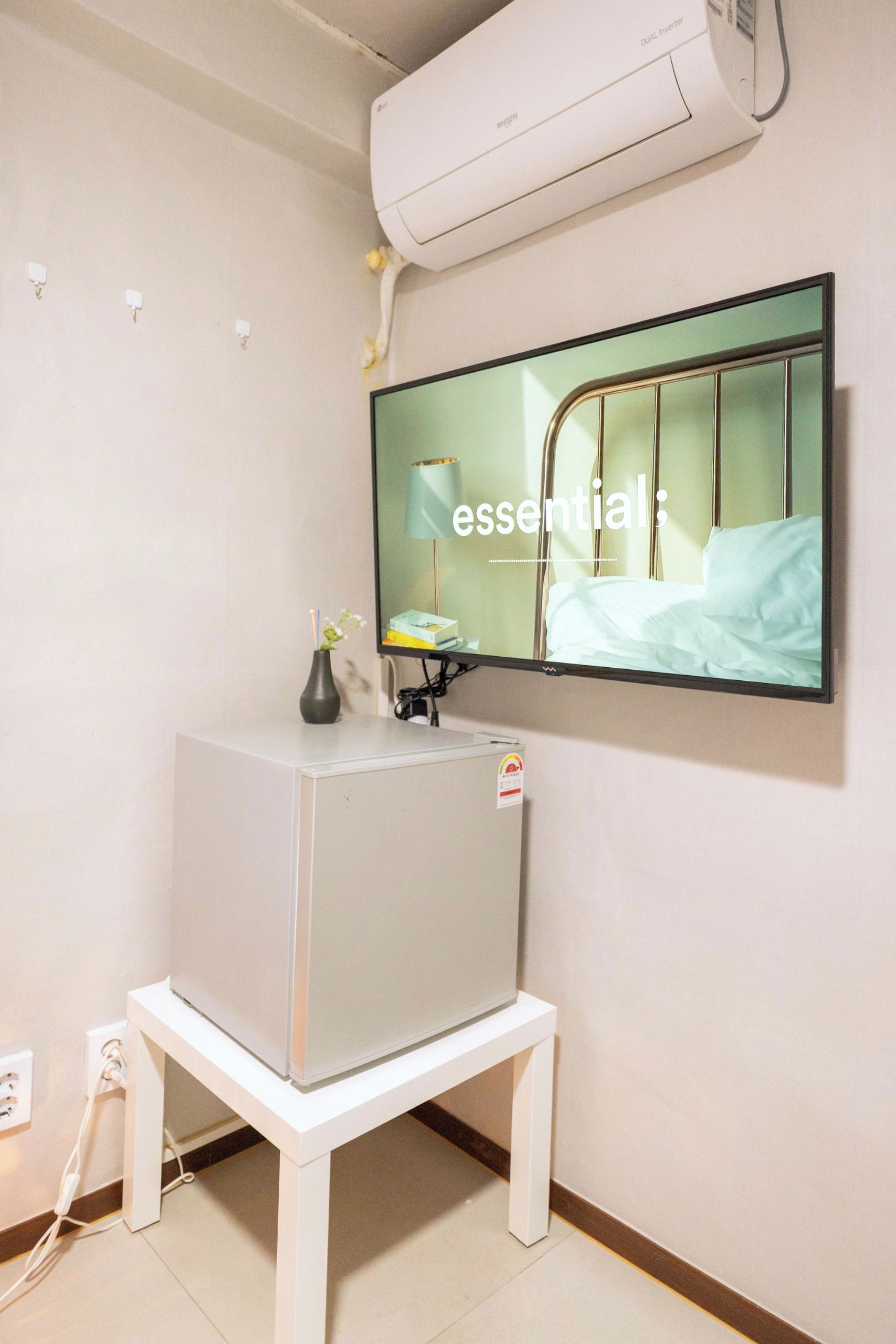 A room with a bed, a wall-mounted TV, and a white cabinet.
