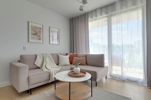 A modern living room with a sofa, a coffee table, and two framed artworks on the wall. - Slow Seaside Brzeźno by Lion Apartments (Gdańsk)