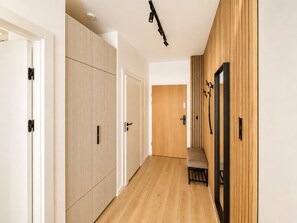 A hallway with a wooden floor, white walls, and a wooden door with a black handle. - Slow Seaside Brzeźno by Lion Apartments (Gdańsk)