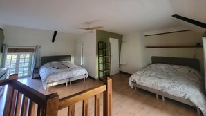 A bedroom with two beds, a ceiling fan, and a window.