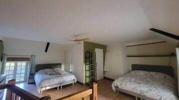 A bedroom with two beds, a ceiling fan, and a window.