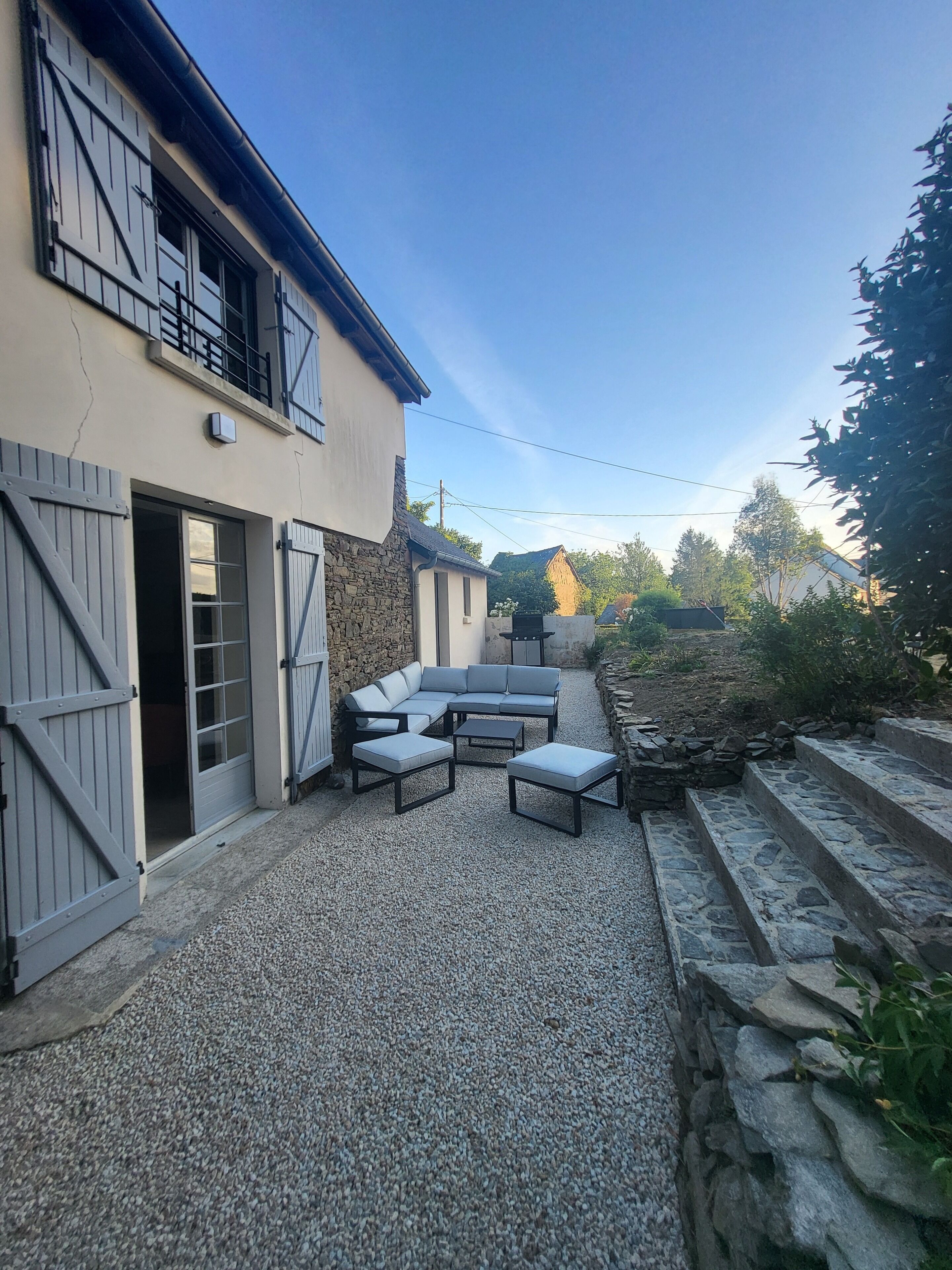A patio area with a stone floor, a built-in seating arrangement, and a stone wall.