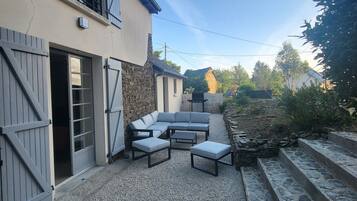 A patio area with a stone floor, a built-in seating arrangement, and a stone wall.