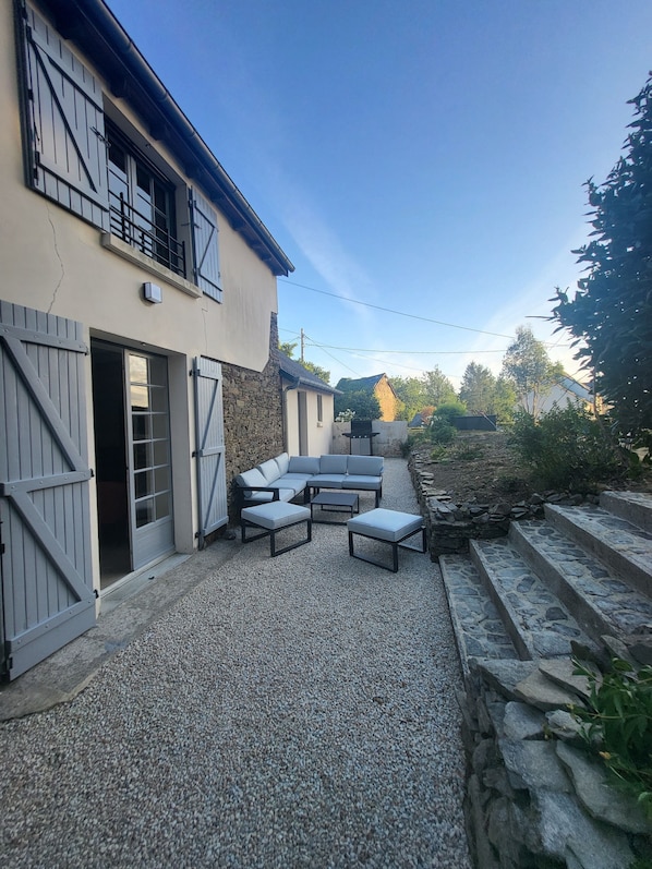 A patio area with a stone floor, a built-in seating arrangement, and a stone wall.