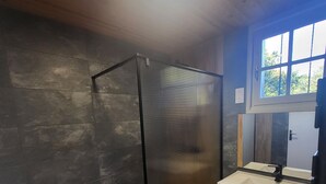 A modern bathroom with a glass shower enclosure, a wooden vanity, and a large mirror.