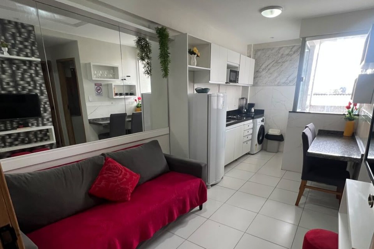 A modern kitchen with white cabinets, a built-in oven, and a dining area with a table and chairs.