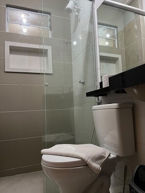 A bathroom with a toilet, a glass shower enclosure, and a mirror above the sink. - Apto 303 2 Qtos 15 min do Centro (Belém)