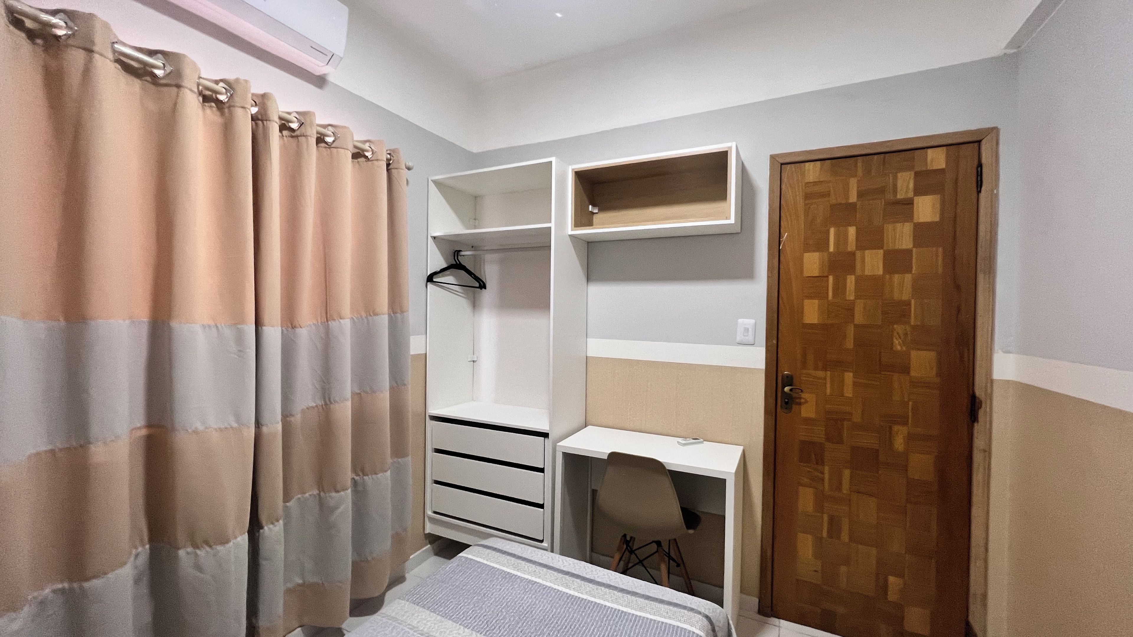 Un dormitorio con cama, armario, escritorio y puerta.