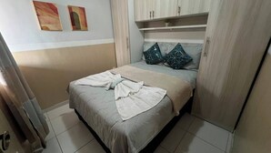 Ein Schlafzimmer mit einem Bett, einem Kleiderschrank und einem Regal darüber.