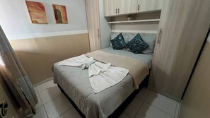 A bedroom with a bed, a wardrobe, and a shelf above the bed. - Apto 303 2 Qtos 15 min do Centro (Belém)