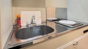 Una cocina moderna con un lavamanos de acero inoxidable, un horno empotrado y un microondas.