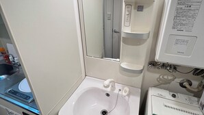 Un baño pequeño con lavamanos, espejo y un mueble de almacenamiento.
