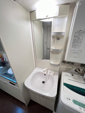Ein kleines Badezimmer mit Waschbecken, Spiegel und einem Hängeschrank.