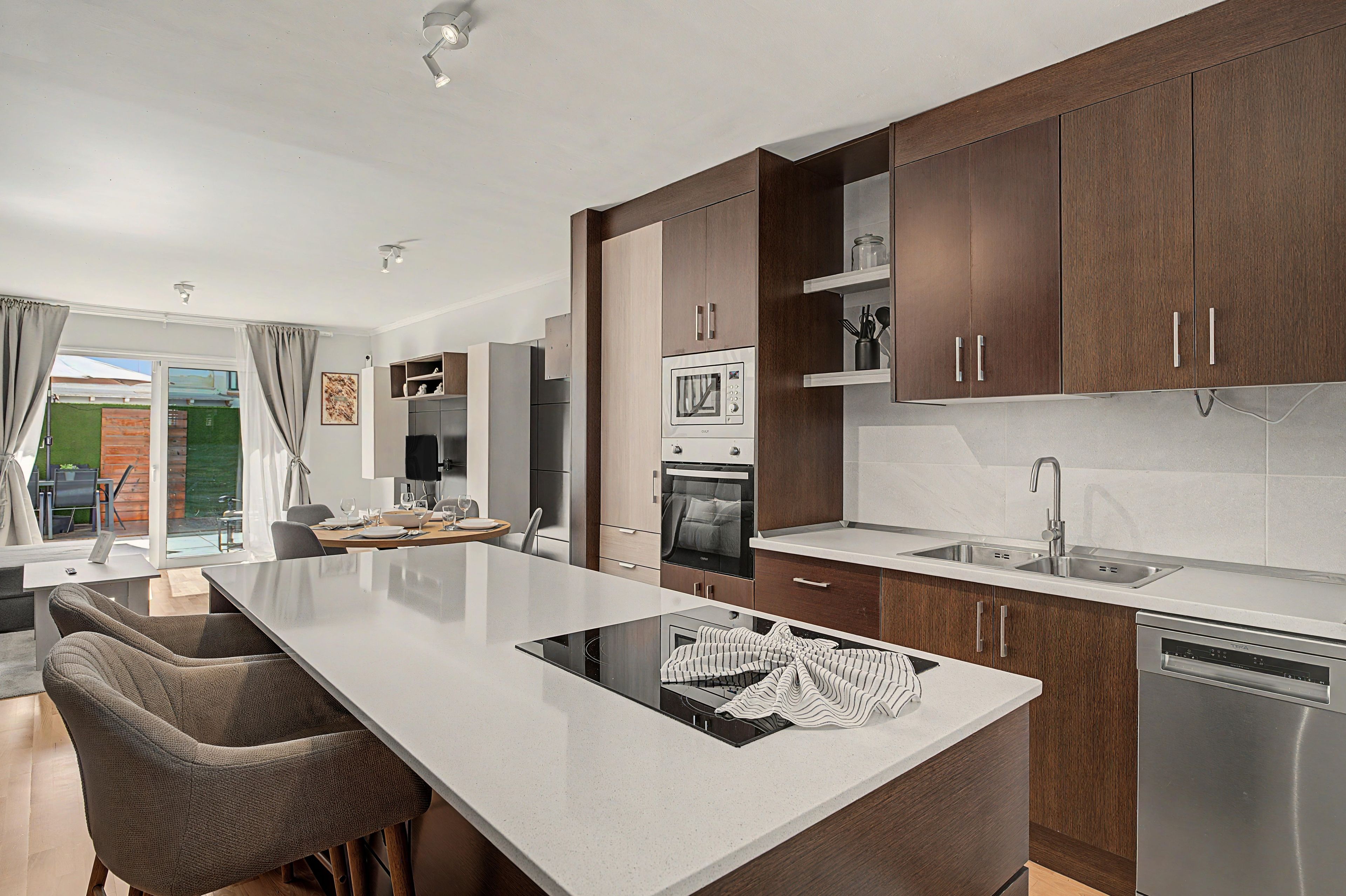 A modern kitchen with a central island, stainless steel appliances, and wooden cabinetry.