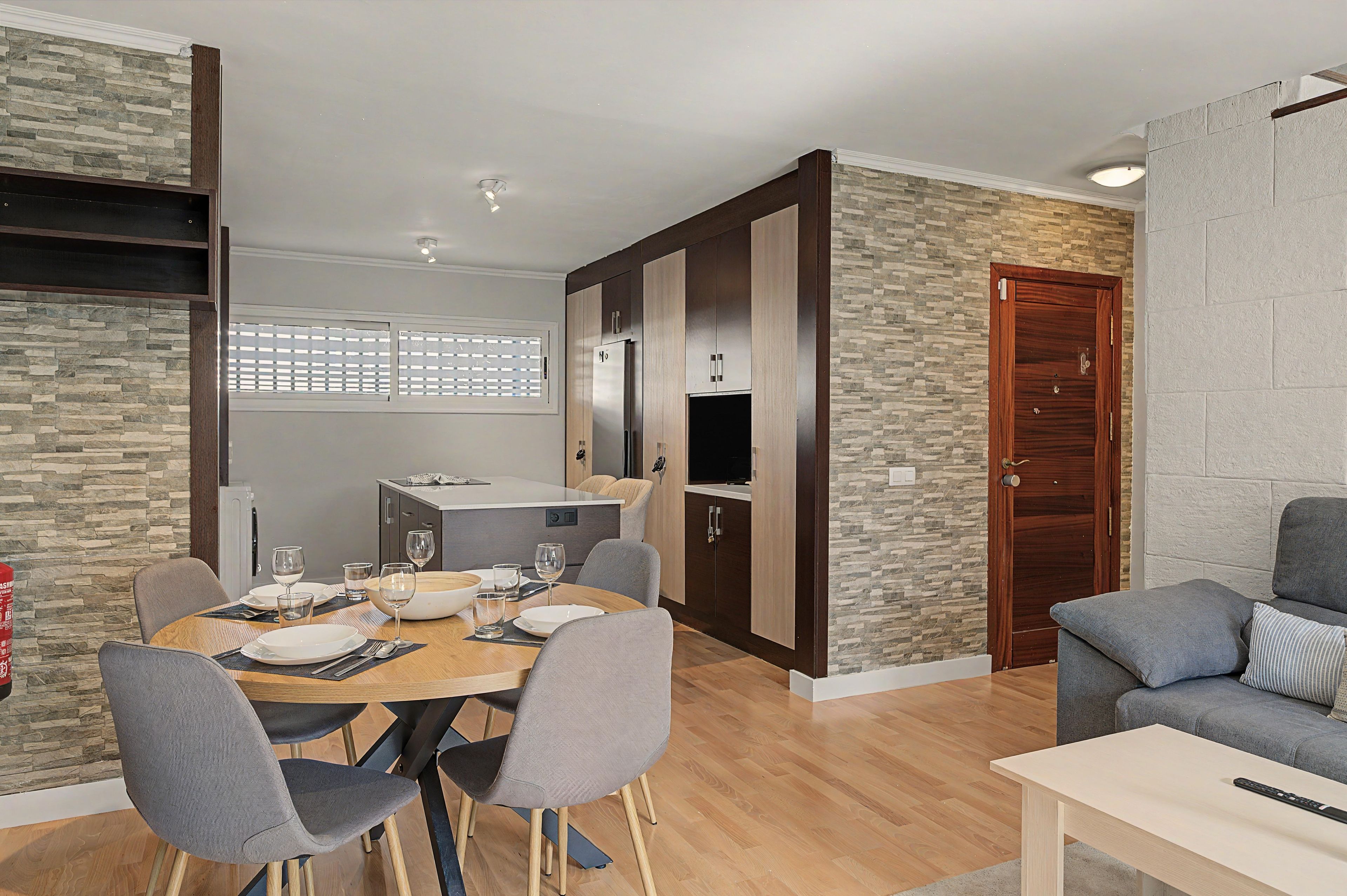 A modern living space with a dining area, a kitchen, and a seating area.