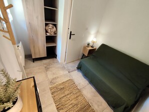 A bedroom with a bed, a bedside table with a lamp, a wardrobe, and a small plant.