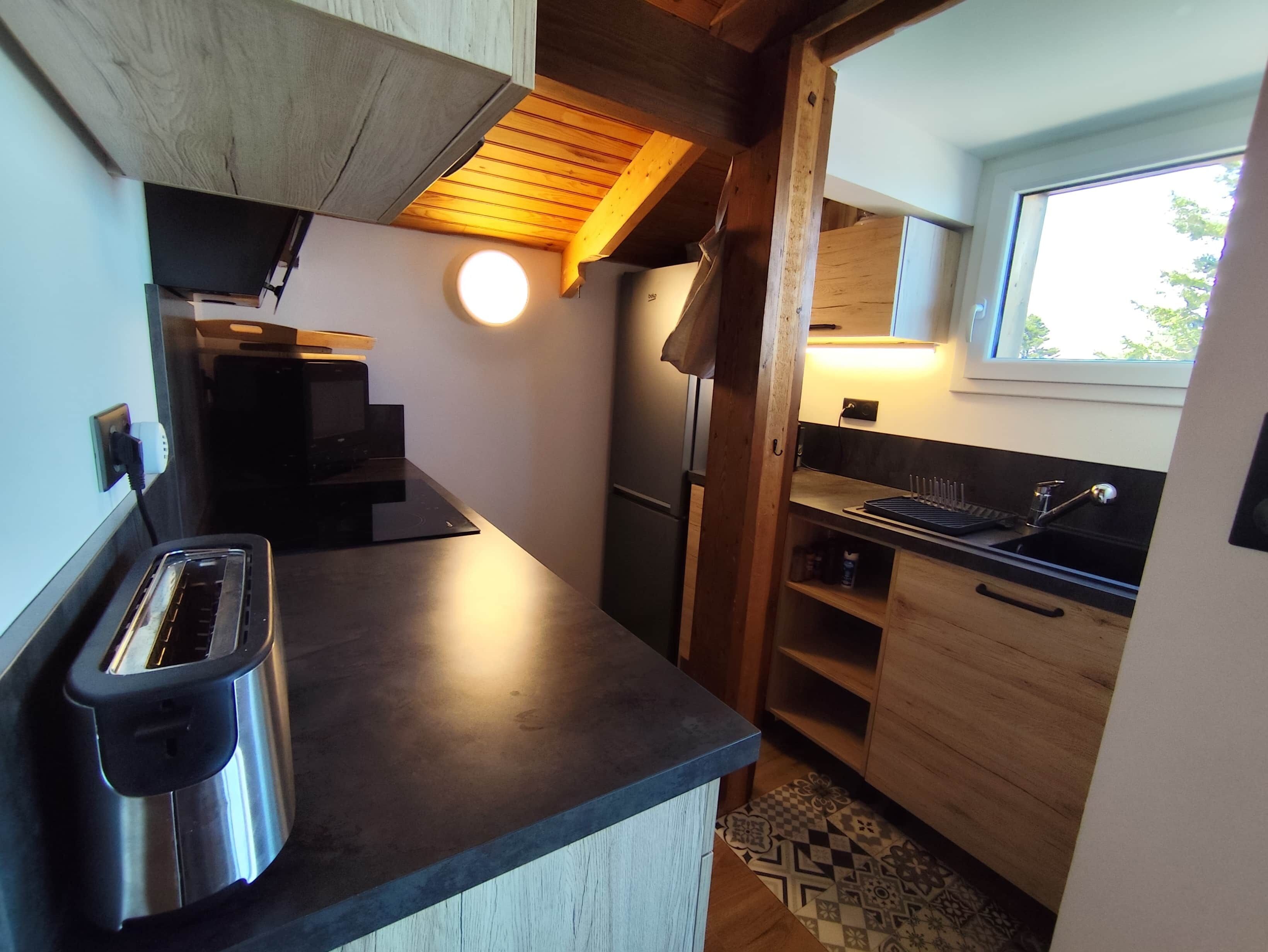 Une petite cuisine équipée d’un grille-pain, d’un réfrigérateur et d’une fenêtre.