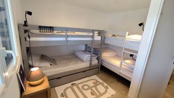 A room with bunk beds, a bedside table with a lamp, and a rug with a road and car design.