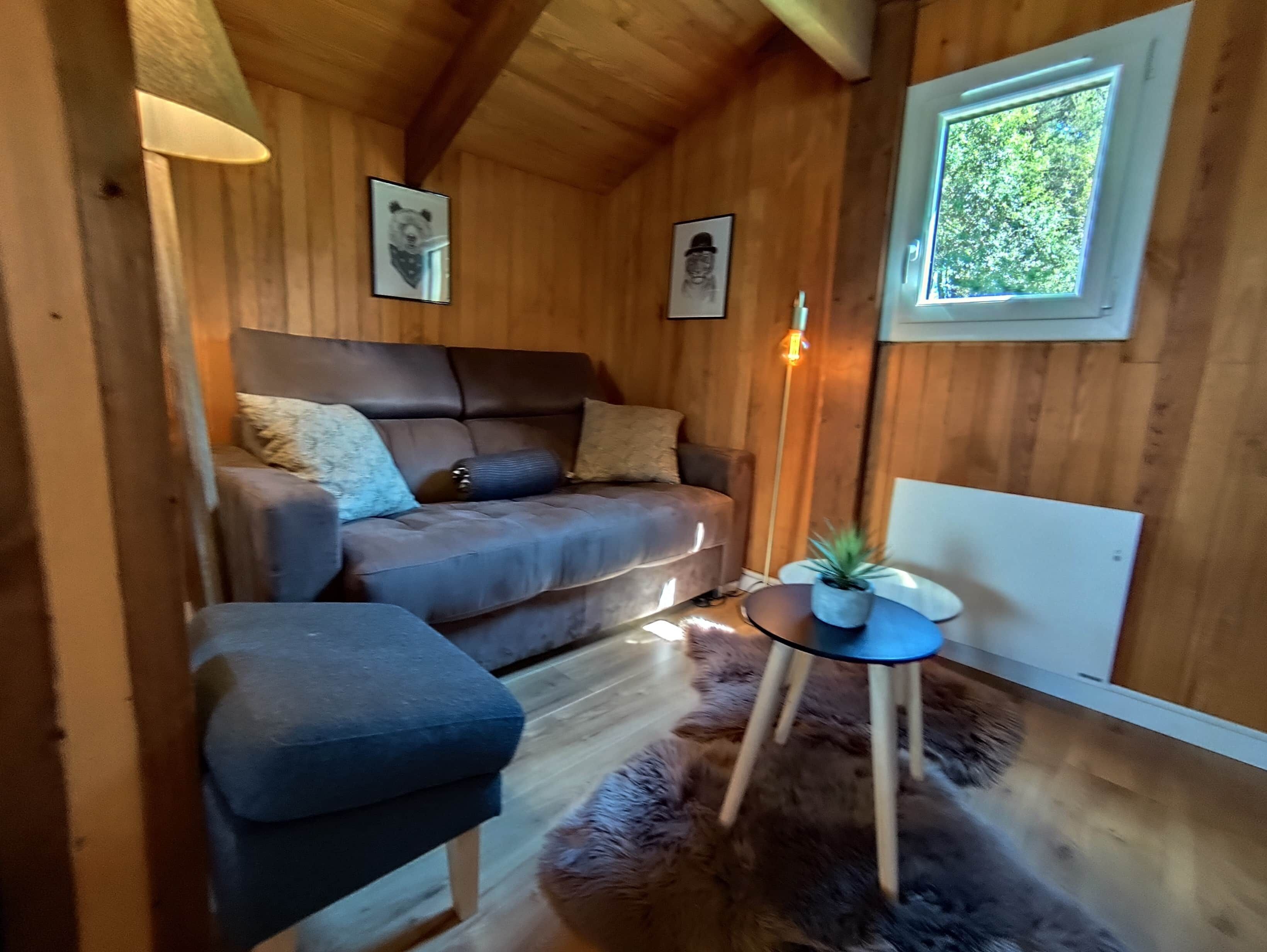 Une pièce confortable avec un canapé, une petite table ornée d’une plante et une fenêtre.