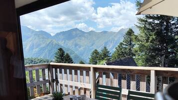 A wooden deck with a table set for dining, overlooking a mountainous landscape.