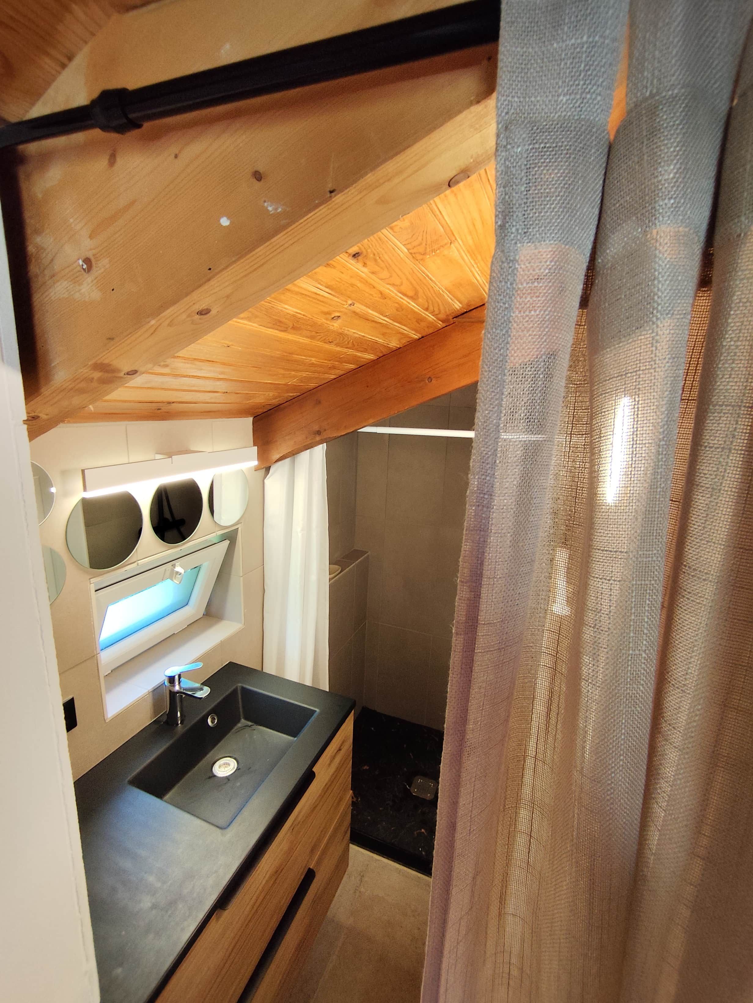 Een kleine keuken met een spoelbak, houten balken in het plafond en een klein aanrecht.