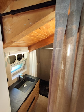 A compact kitchen with a sink, wooden ceiling beams, and a small countertop.