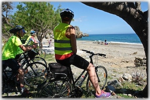 Eine Strandlandschaft mit Radfahrern und freiem Blick auf den Ozean.