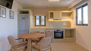 Una cucina compatta con zona pranzo, elettrodomestici integrati e ampie finestre.