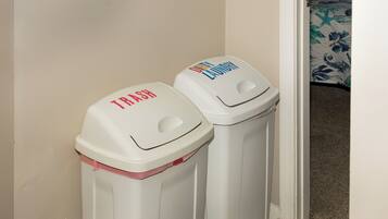 Two trash bins with labels 'TRASH' and 'DIRTY LAUNDRY' in a hallway.
