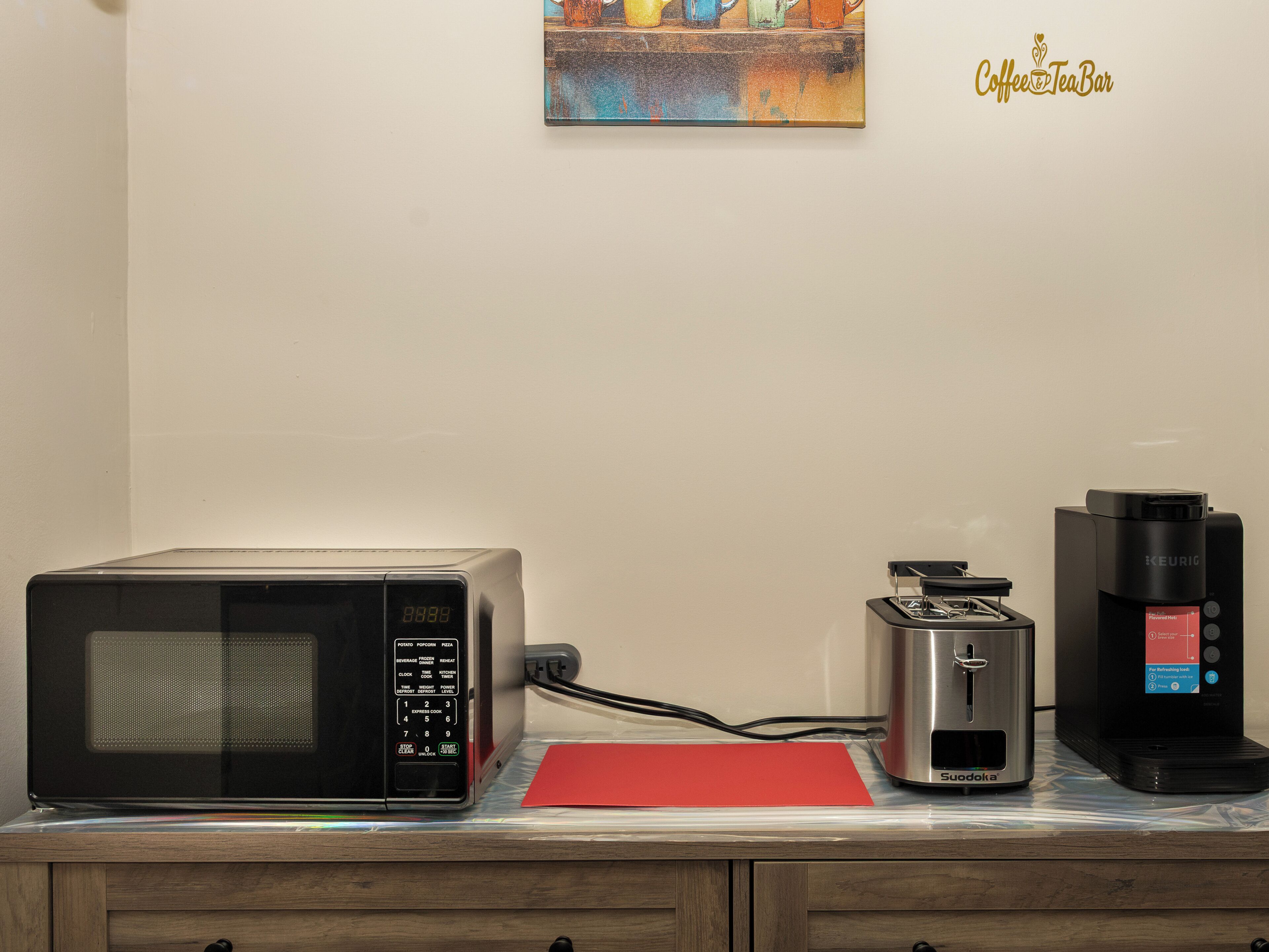 Une petite cuisine équipée d’un four à micro-ondes, d’un grille-pain et d’une machine à café, le tout posé sur un plan de travail.