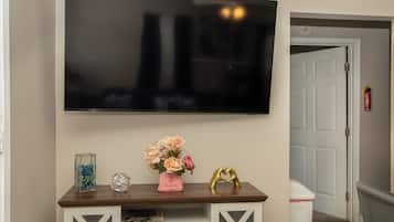 Uma TV de tela plana fixada na parede acima de um console de madeira com objetos decorativos.