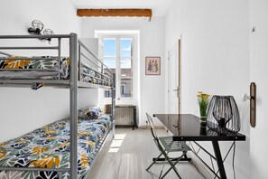 Um quarto de estudante com beliches, escrivaninha e cadeira.