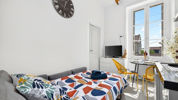 Habitació compacte amb un llit, una televisió, una taula de dinar petita i una finestra amb vistes.