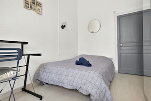 Ein Schlafzimmer mit einem Bett, einem Sessel, einem Kleiderschrank, einem Spiegel und einer Wand mit gerahmten Bildern.