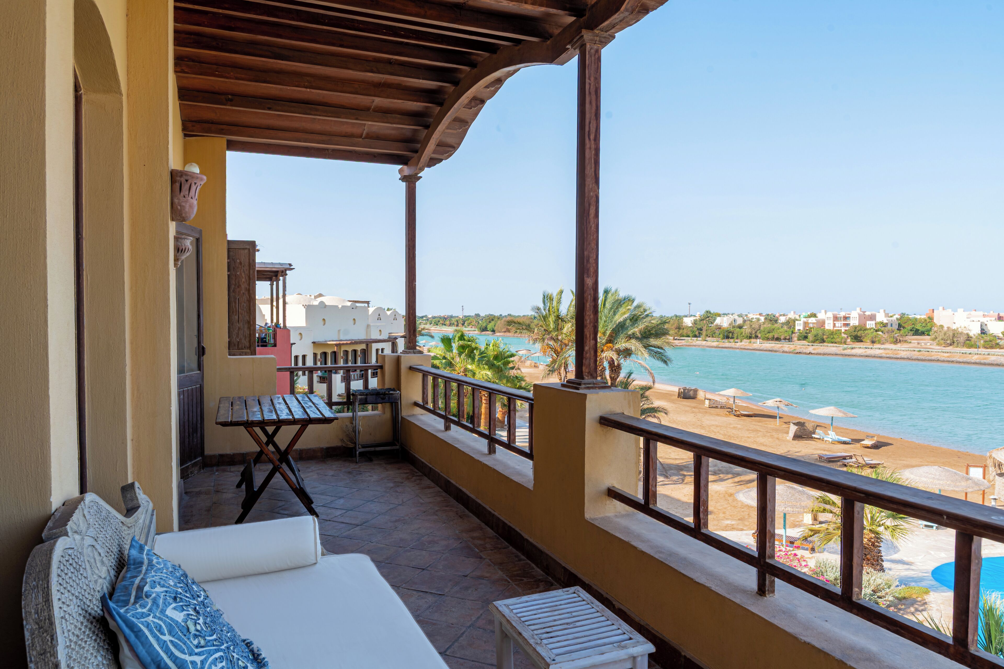 A balcony with a view of the sea, a table, a sofa, and a small table.