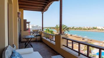 A balcony with a view of the sea, a table, a sofa, and a small table.