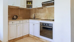 Una cucina con mobili bianchi, un fornello e un lavello.