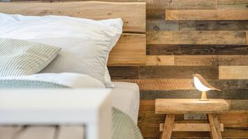 Un lit avec des oreillers, une tête de lit en bois et une table de chevet avec une lampe et une petite sculpture en bois.
